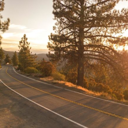 The sun sets on a winding country road lined with trees