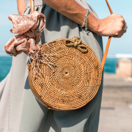 Person on a beach clutching a summer essential handbag