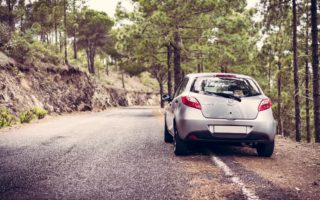 A grey car parked on the right-hand side of a country road as the driver stops to make their journey more fun
