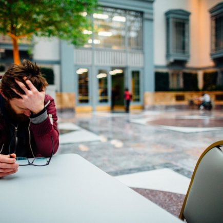 Man sat with head in his hands dealing with anxiety.