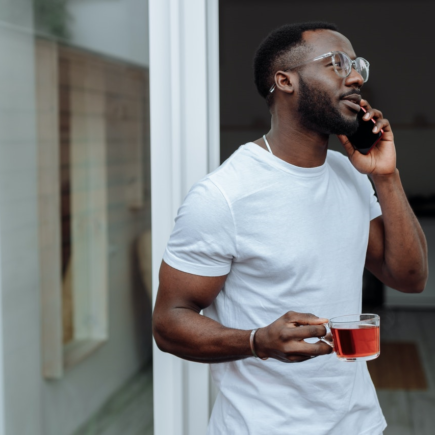 a man on a phone call drinking a healthy herbal tea while working from home