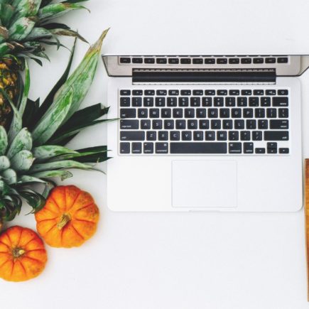Laptop on a desk with fruit and vegetables next to it for a healthy snack while working from home.